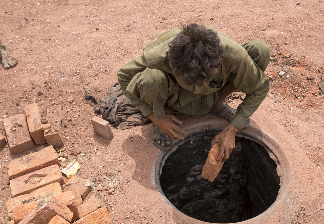 Een arbeider bij een steenfabriek controleert het bakproces van de stenen in de steenoven
