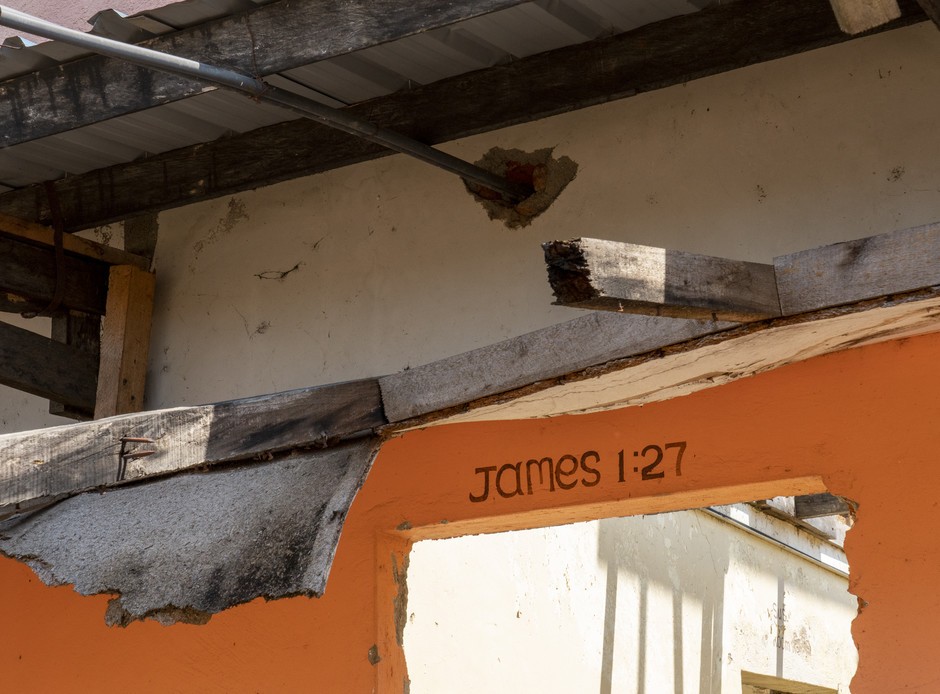 Op het verwoeste gebouw wordt Jakobus 1:27 aangehaald