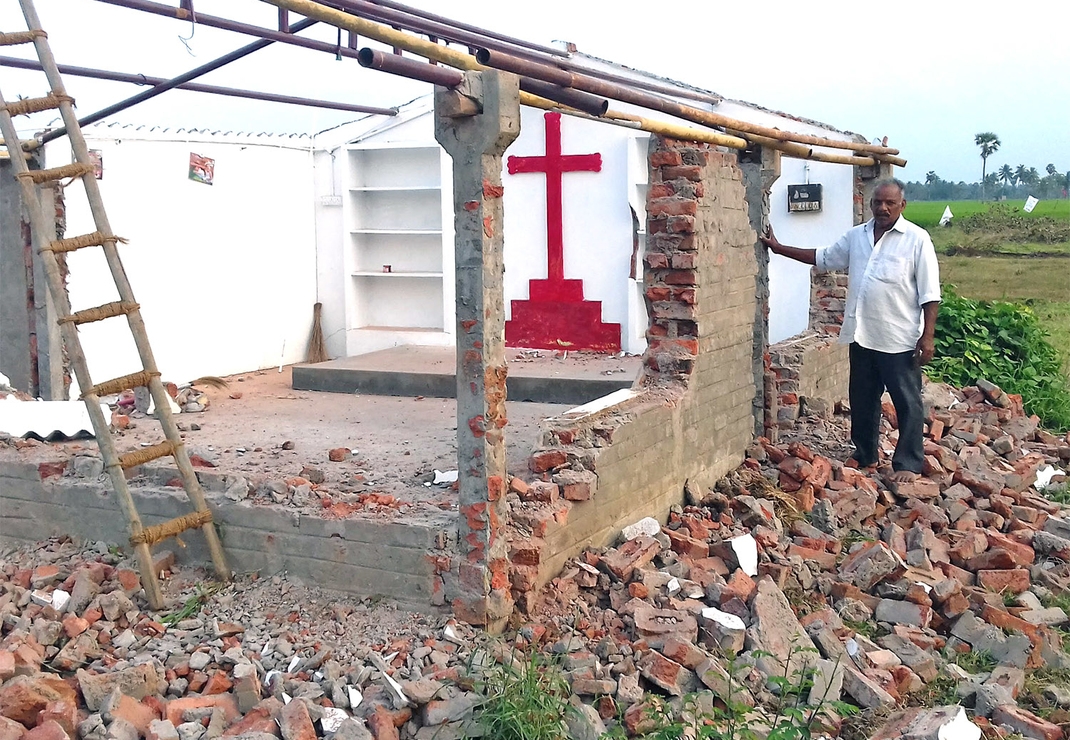 Evangelist Abraham bij het beschadigde kerkgebouw voordat de bulldozer het met de grond gelijk maakte