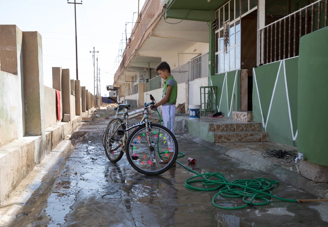 Een jongen wast zijn fiets in Qaraqosh