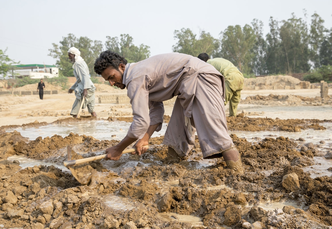 Het werk in de steenfabriek gebeurt handmatig. Het dagelijks mengen van zand en water tot modder leidt tot rugklachten bij de werkers.