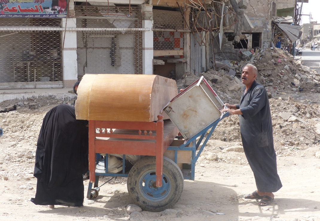 Irak: een man keert met al zijn bezittingen op een kar terug naar de kapot geschoten stad Ninevé (Mosul)