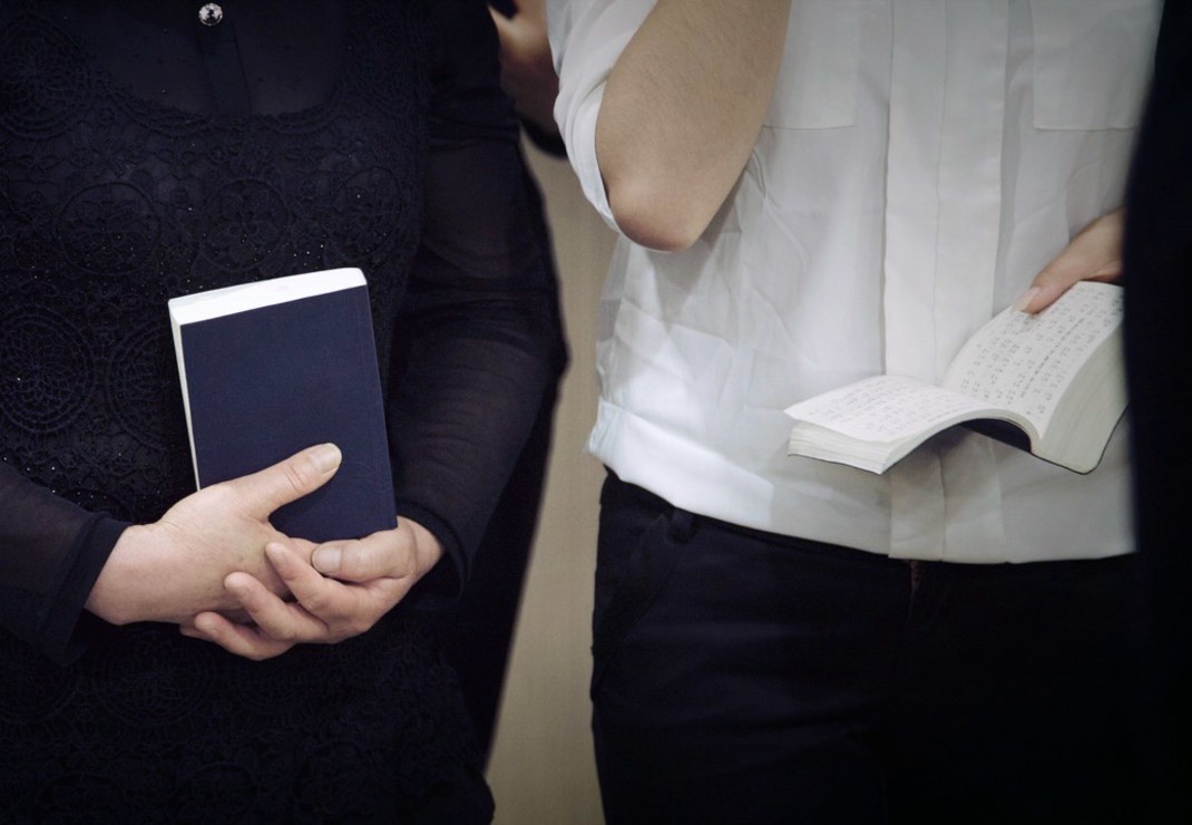 Geen christen draagt een Bijbel of zangbundel zo openlijk. Afgebeeld zijn 'leden' van een staatskerk, waarmee de overheid de schijn probeert te wekken van geloofsvrijheid.