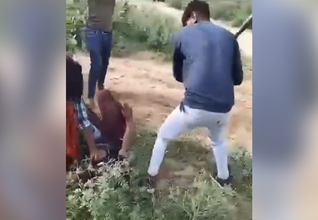 De video laat zien hoe de man tegen de grond wordt gedrukt terwijl twee andere aanvallers op hem inslaan met stokken