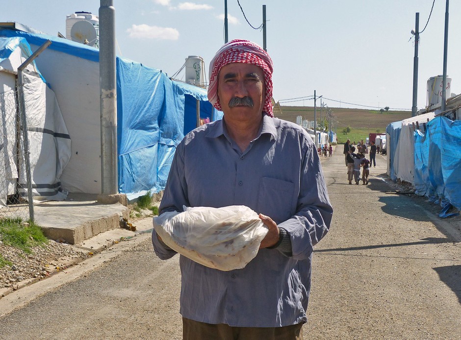 Een vluchteling loopt terug naar zijn tent met zijn verse brood