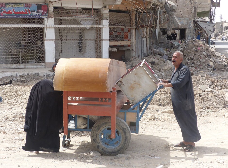 Een man keert met al zijn bezittingen op een kar terug naar de kapot geschoten stad Ninevé (Mosul)